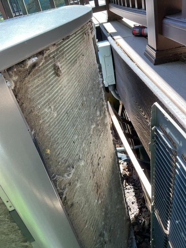 # HVAC Cooling Maintenance Service

Performed comprehensive cooling system maintenance on outdoor condensing unit. Upon arrival, conducted initial system diagnostics and temperature measurements, recording ambient conditions at 53.6°F using digital measuring instrument. 

Inspection revealed heavy accumulation of dirt, dust, and debris on condenser coil fins, significantly impacting heat transfer efficiency. The vertical fins displayed extensive contamination with grayish-brown buildup and organic matter throughout the coil surface, indicating extended operation without regular maintenance. This level of fouling restricts airflow and reduces system capacity, causing increased energy consumption and potential compressor strain.

Cleaned condenser coil thoroughly to restore proper airflow and heat exchange capabilities. Removed environmental contaminants and debris from coil surfaces and unit base. Verified refrigerant line connections and inspected copper piping for proper installation 