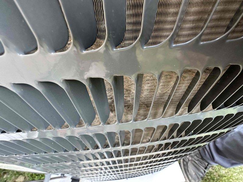 # HVAC Cooling Maintenance Completed

Performed comprehensive preventive maintenance service on residential air conditioning system as part of ongoing cooling season maintenance program. Conducted thorough inspection of outdoor condenser unit, evaluating heat exchanger coils and aluminum fin assembly for operational efficiency and airflow restrictions.

Upon inspection, identified moderate to heavy accumulation of dirt, dust, and debris on condenser coil fins, particularly concentrated in lower sections of the heat exchanger. Noted visible discoloration and brownish buildup on fin surfaces indicating extended exposure to airborne contaminants. Observed white mineral deposits and frost-like buildup on horizontal refrigerant tubes connecting upper and lower coil assemblies, suggesting potential drainage or moisture-related issues requiring monitoring.

Documented current condition of heat exchanger fins through photographic evidence, capturing areas of heavy soiling and oxidation on meta