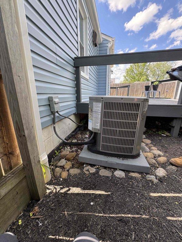 Replaced deteriorated condenser pad with new composite pad and re-leveled outdoor AC unit to ensure proper drainage and equipment stability. Unit was repositioned on the new pad with appropriate clearances maintained from the house siding and surrounding landscape, with refrigerant lines and electrical connections verified secure after installation.