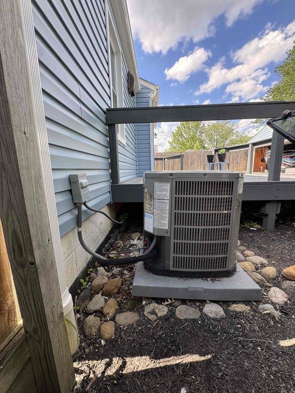 Replaced deteriorated condenser pad with new composite pad and re-leveled outdoor AC unit to ensure proper drainage and equipment stability. Unit was repositioned on the new pad with appropriate clearances maintained from the house siding and surrounding landscape, with refrigerant lines and electrical connections verified secure after installation.