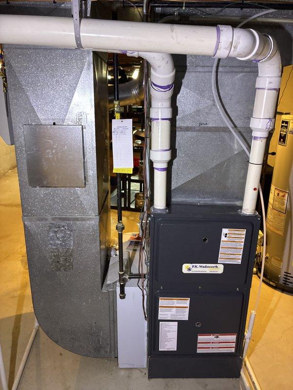 Conducted on-site assessment of existing HVAC system in basement utility area to provide replacement options for air conditioning equipment. Evaluated current furnace and air handler configuration, noting accessible installation location with adequate clearance for equipment service and replacement. Documented existing ductwork assembly, PVC drainage lines, and ventilation routing to determine compatibility requirements for new AC system integration. Photographed current equipment layout showing furnace unit, wrapped ductwork, horizontal and vertical PVC piping with proper mounting supports, and surrounding mechanical components. Prepared two AC replacement options tailored to the straightforward access conditions and existing infrastructure, accounting for the organized installation space and proper support structures already in place.