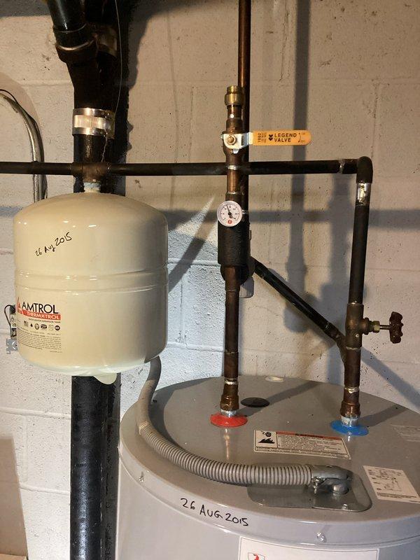 Conducted on-site evaluation for residential water heater replacement. Assessed existing installation including 2015-vintage water heater, AMTROL expansion tank, copper supply lines with isolation valves, pressure relief components, and corrugated flexible connector at base. Documented current plumbing configuration with brass fittings, pressure gauge, and foam pipe insulation on vertical runs. Provided estimate for new water heater installation with expedited service requested by customer.