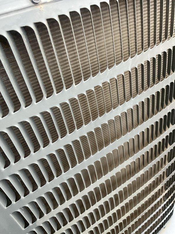 Completed comprehensive cooling system tune-up on residential air conditioning unit. Performed thorough inspection of condenser coils, noted significant organic growth and discoloration on exterior grille requiring attention, and verified proper operation of top-mounted fan assembly and heat exchanger components.