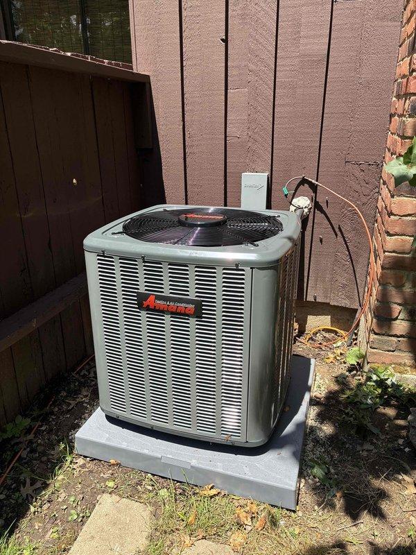 Completed installation of new Amana air conditioning system including outdoor condensing unit and indoor evaporator coil. Outdoor unit was positioned on concrete pad with proper clearances, electrical disconnect installed, and all refrigerant lines connected and tested. Indoor evaporator coil was mounted above existing furnace with insulated ductwork and drainage lines properly configured. System was charged, tested for proper operation, and all safety controls verified functional.