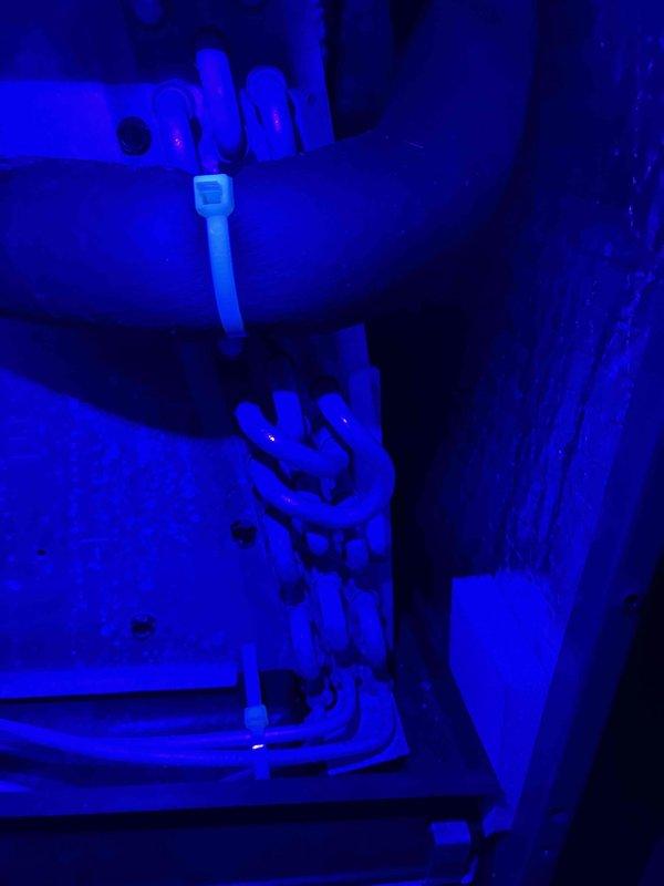 Returned for follow-up inspection one week after UV dye injection to locate refrigerant leak. Utilized ultraviolet lighting to examine refrigerant lines and connections throughout system. UV dye trace revealed leak location on copper refrigerant piping. Verified supply air temperature reading of 50.1°F at ductwork to confirm system performance during inspection.
