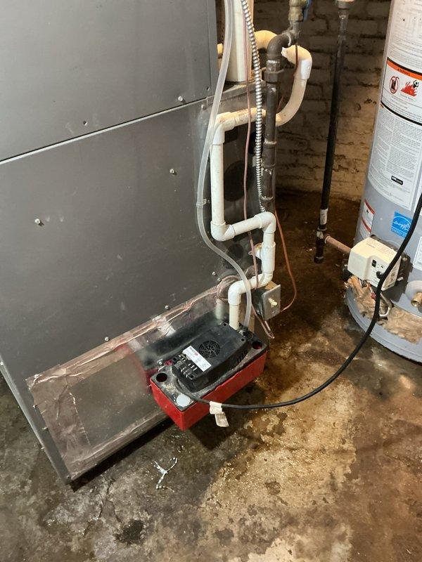 Responded to service call for air conditioning system experiencing electrical issues and water leakage. Upon inspection, found water accumulation on basement floor near air handler unit with visible staining indicating ongoing drainage problem. Identified malfunctioning red condensate pump at base of air handler as primary cause of water leak. Evaluated electrical connections to condensate pump and verified proper operation of drainage system. Inspected PVC condensate drain lines for blockages or improper pitch. Tested air handler operation and confirmed system functionality after addressing drainage issue. Provided customer education on maintenance value plan benefits and recommended enrollment for preventative maintenance including regular thermostat verification, ductwork inspection, blower wheel cleaning, electrical component testing, and heat exchanger diagnostics to prevent future issues.