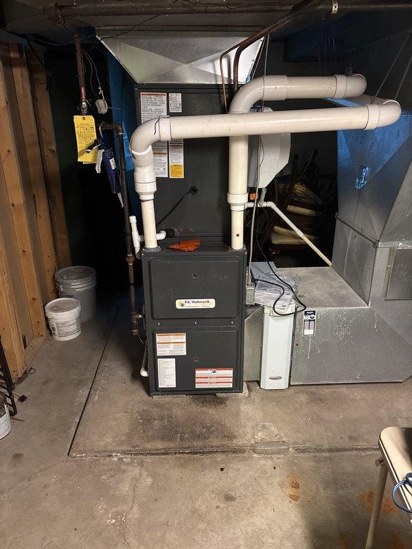 Completed installation of new air conditioning system in basement utility area. Installed air handler unit with associated electrical connections and conduit work, configured PVC venting system in U-shaped configuration for proper intake and exhaust, and connected sheet metal ductwork to integrate with existing furnace system. All equipment mounted on concrete floor per manufacturer specifications, electrical components properly wired and secured, and system tested for proper operation upon completion.