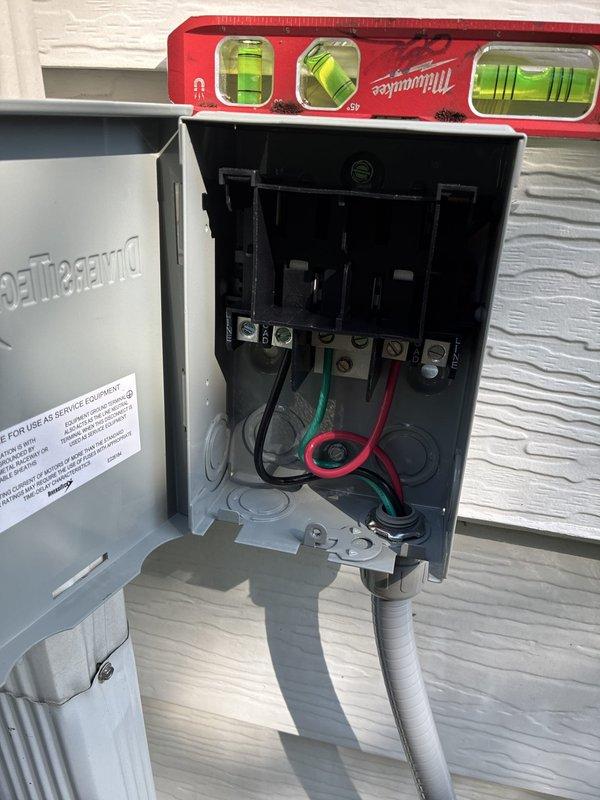 Completed mini split installation with TropiCool disconnect box mounted on exterior wall with proper conduit routing and electrical connections to terminal blocks. Electrical hookup scheduled for completion on 6/25 due to service financing requirements; unit installation and disconnect box placement verified level and secure.