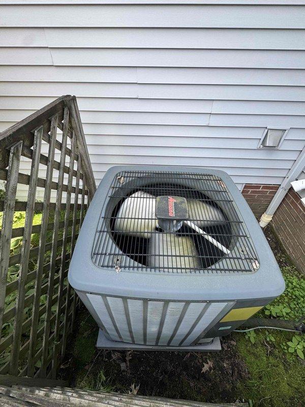 Completed scheduled preventive maintenance on residential Amana air conditioning condenser unit. Performed comprehensive system inspection including visual assessment of outdoor unit condition, fan operation, and surrounding clearances. Documented equipment location and operational status with photographic evidence showing unit positioned on pad adjacent to home exterior with adequate access for service. Noted vegetation encroachment around unit base requiring future monitoring to maintain proper airflow clearances.