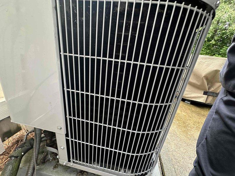 Completed scheduled cooling system maintenance on residential outdoor condensing unit. Performed comprehensive inspection of condenser assembly, verified protective grille cage integrity, checked electrical disconnect box and associated wiring connections, and examined refrigerant line routing. Unit showed normal weathering and environmental debris accumulation consistent with outdoor exposure. All components found to be operational and functioning within normal parameters.