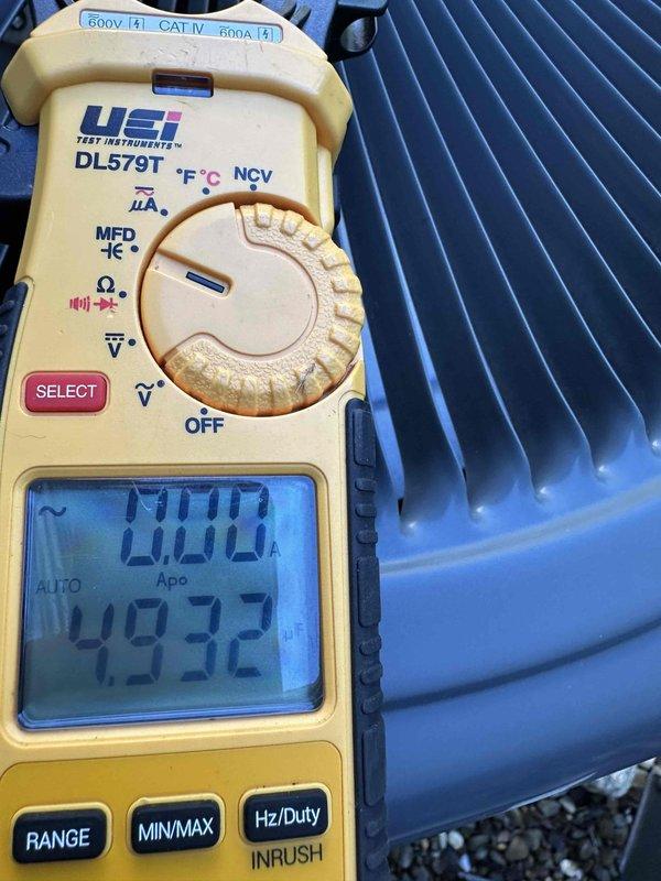 # HVAC Maintenance - Cooling System Service

Completed comprehensive cooling system maintenance inspection on residential air conditioning unit. Performed electrical diagnostics using digital multimeter to verify amperage draw and system performance parameters, recording readings of 0.00A and 49.32 on measurement device. Inspected condenser coil fins for proper airflow and heat transfer efficiency, noting blue-colored aluminum fin condition. Examined refrigerant service valves and brass fittings at compressor connections, verifying proper sealing and mechanical integrity of valve assemblies with spring-loaded components. Assessed system components for wear, corrosion, and operational readiness as part of recurring preventive maintenance program.
