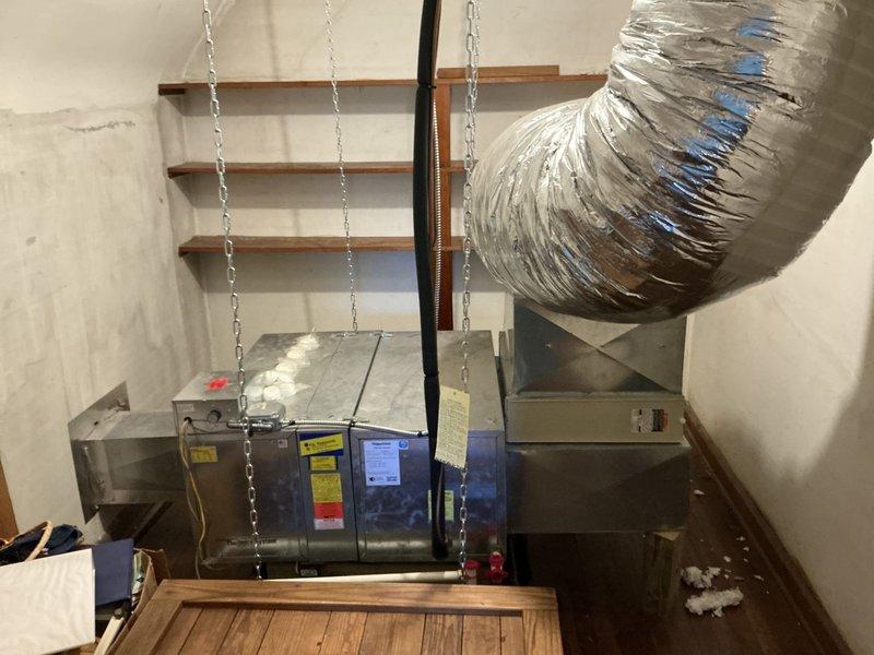 Completed full HVAC system replacement including installation of new air handling unit suspended from ceiling joists with chain mounting hardware in mechanical space. Connected flexible aluminum ductwork with secure fastening straps and installed wall-mounted equipment cabinet. Installed new ceiling-mounted sensor or detector device in finished living space to integrate with replacement system.
