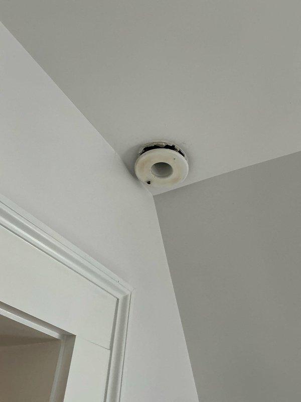 Completed full HVAC system replacement including installation of new air handling unit suspended from ceiling joists with chain mounting hardware in mechanical space. Connected flexible aluminum ductwork with secure fastening straps and installed wall-mounted equipment cabinet. Installed new ceiling-mounted sensor or detector device in finished living space to integrate with replacement system.