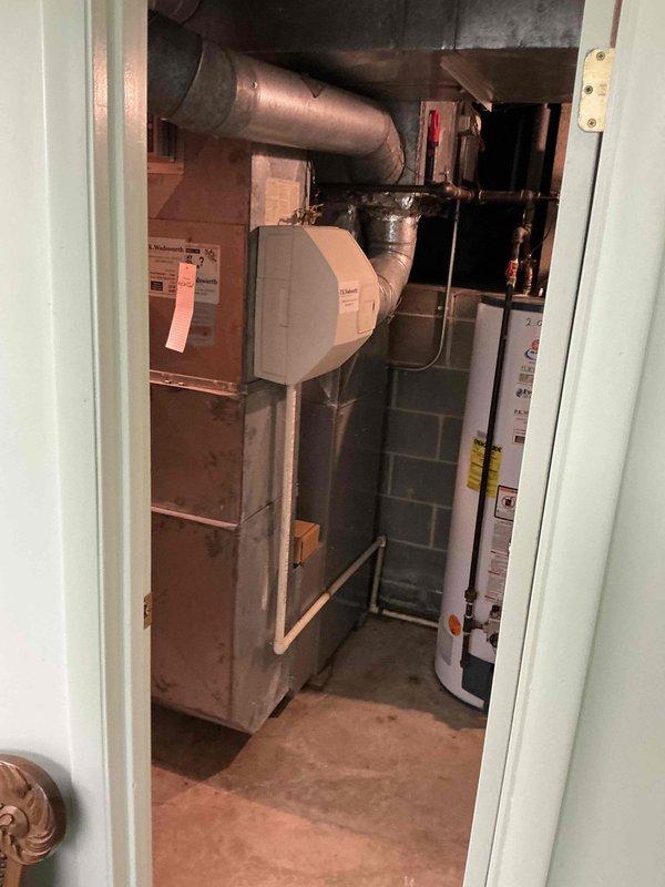 Conducted comprehensive estimate evaluation for furnace replacement in residential property. Assessed existing brown/tan metal furnace unit with side-mounted humidifier system, documented current thermostat configuration (White-Rodgers digital unit), and evaluated overall HVAC system layout including existing ductwork and mechanical room conditions. Provided homeowner with multiple furnace replacement options based on equipment age, configuration, and space requirements.