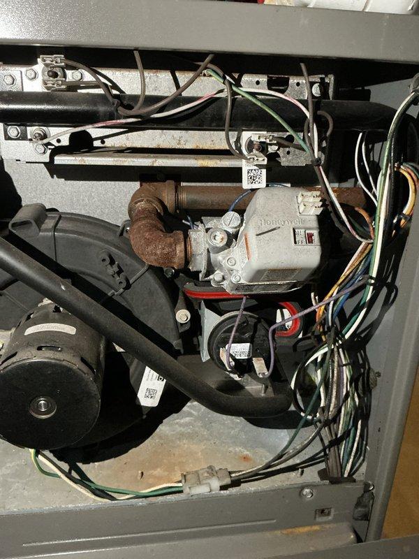 Conducted comprehensive assessment of existing HVAC system in basement mechanical room and presented full system replacement options. Evaluated current furnace/air handler unit showing signs of age and wear, including corroded gas valve components and rusted piping connections on Honeywell control assembly. Documented existing equipment configuration including ductwork layout, electrical connections, and integration with water treatment systems for complete replacement planning.