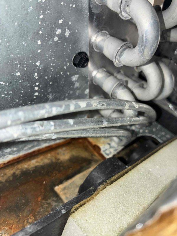 Performed two comprehensive leak searches on rooftop HVAC condensers. Connected manifold gauges to refrigerant system, conducted pressure testing, and inspected all refrigerant lines, coil connections, and internal components for leaks. Evidence of moisture exposure and corrosion observed in drain pan area during internal inspection.