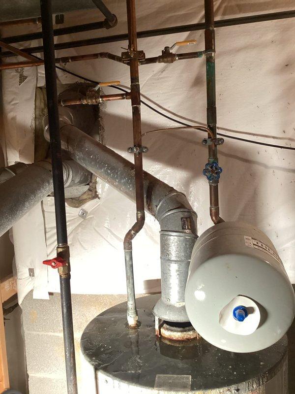 Responded to no hot water call and inspected Lochinvar residential water heater system in utility room. Identified moisture accumulation on galvanized piping and verified all plumbing connections, shut-off valves, copper piping, expansion tank, and safety components were functioning properly. System restored to normal operation with hot water service confirmed.