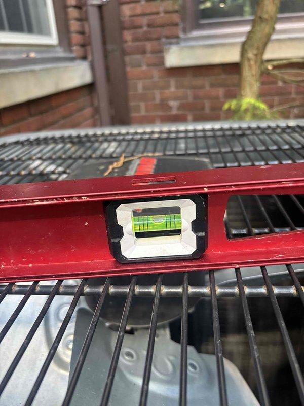 Leveled outdoor condensing unit that had settled unevenly on concrete pad. Used precision level to verify proper positioning and adjusted unit to ensure optimal performance and prevent potential compressor damage from improper orientation. Unit now sits level on pad with correct drainage pitch maintained.