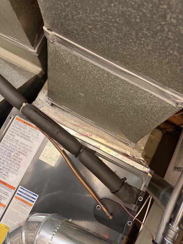 Performed warranty inspection on recent HVAC installation to address code compliance issue identified during initial inspection. Documented furnace exhaust connection requiring three sheet-metal screws per Residential Code of Ohio 1601.4.1 for proper mechanical fastening of crimp joints on round metallic ducts. Photographed HVAC equipment installation in attic space showing furnace unit, refrigerant lines, and ductwork connections. Additionally documented reported flooring damage in laundry room area, capturing images of laminate flooring with visible staining or discoloration on wood surface. All required photographic documentation completed for re-inspection process.