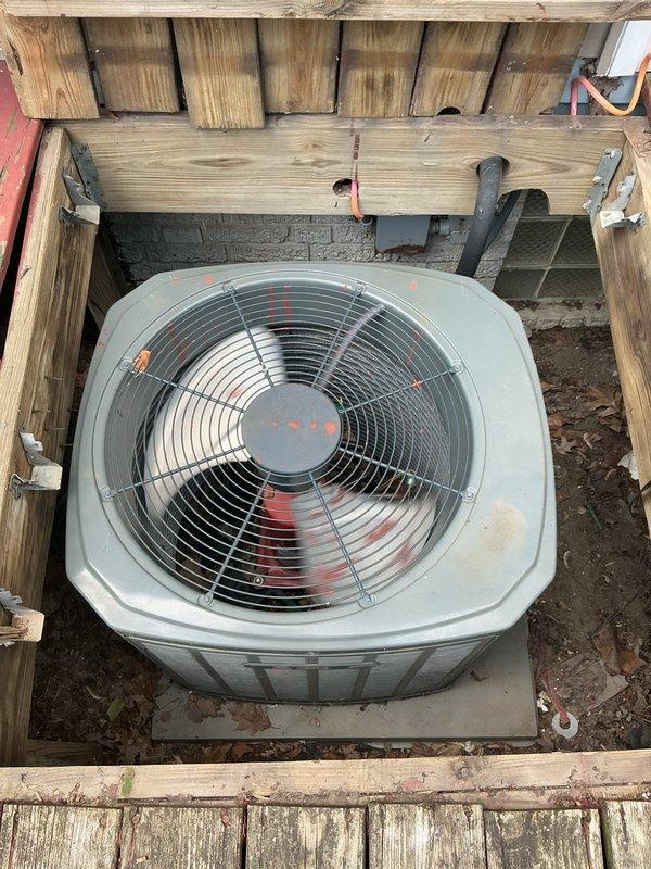 # HVAC Cooling Maintenance Completed

Performed routine preventive maintenance on residential split-system air conditioning unit located beneath elevated deck structure. Conducted comprehensive inspection of outdoor condenser unit, including visual assessment of cabinet condition, fan assembly, and protective grille. Verified proper placement on concrete pad and checked clearances around unit.

Opened electrical compartment and inspected internal components. Identified significant rust and corrosion on capacitor terminal cap, indicating moisture intrusion and potential component degradation. Corrosion was concentrated around terminal connections on top of dual-run capacitor. Noted wiring connections remained intact with red and gray/blue conductors properly terminated to capacitor posts.

Documented equipment condition through photographic documentation for maintenance records. Unit operational at time of service. Recommended monitoring capacitor performance and considering replacement