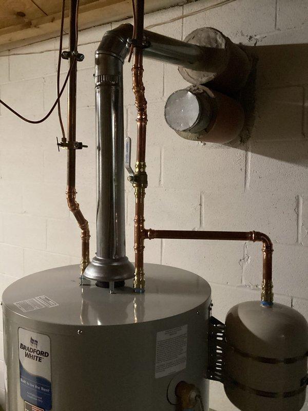 Replaced 50-gallon Bradford White residential water heater in basement utility area with complete installation including all current code-required upgrades. Installation included proper venting with metal flue pipe, copper supply line connections with shutoff valves, expansion tank mounting, and PVC discharge piping, ensuring system meets all local plumbing and safety code requirements.