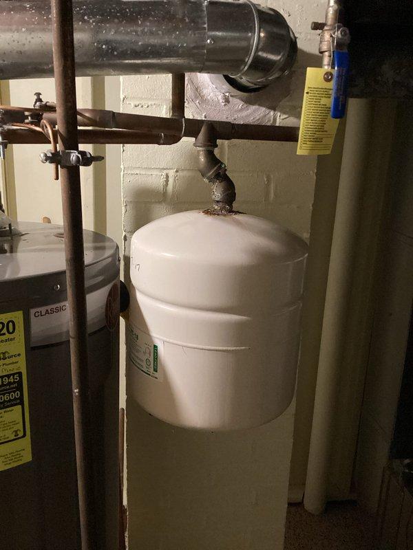 Completed comprehensive plumbing inspection of residential basement mechanical systems. Documented existing expansion tank installation with copper piping connections and identified significant corrosion and rust accumulation at cast iron pipe joints above water heater, indicating potential leak points requiring future attention.