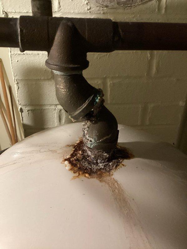 Completed comprehensive plumbing inspection of residential basement mechanical systems. Documented existing expansion tank installation with copper piping connections and identified significant corrosion and rust accumulation at cast iron pipe joints above water heater, indicating potential leak points requiring future attention.