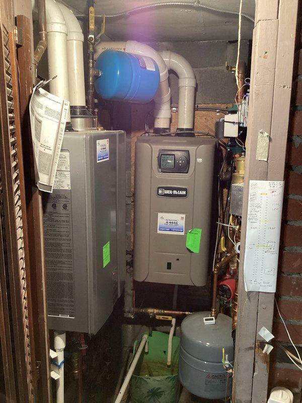 Responded to reported possible hot water system pipe leak at residential property with mechanical systems dating to 1969. Conducted thorough visual inspection of utility room containing Weil-McLain water heater, furnace unit, expansion tanks, and associated copper and PVC piping infrastructure. Examined all visible pipe connections, joints, valves, and fittings throughout the heating and domestic water distribution system for signs of active leakage, moisture accumulation, corrosion, or mineral deposits. Inspected pressure tank, expansion tank, and circulator pump assembly with red-handled valve for potential leak sources. Assessed condition of copper supply lines, return lines, and various brass fittings connecting system components. Photographed equipment configuration and piping layout for documentation purposes. No active leaks were identified during visual inspection of accessible mechanical equipment and piping at time of service call.