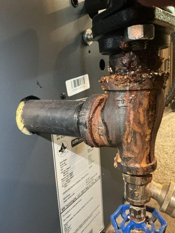 Responded to service call for reported leak on 4-month-old boiler installation. Upon inspection, discovered severe corrosion and active deterioration on steel piping connected to the Taco 007-F5 circulator pump. The vertical pipe section and elbow joint exhibited extensive rust formation and surface flaking, indicating premature failure likely due to improper material selection or water chemistry issues for a recent installation. Documented conditions with photographs showing the corroded fittings, circulator connections, and affected piping assembly. Identified that ferrous piping was experiencing accelerated oxidation inconsistent with the boiler's age, suggesting potential installation defect or incompatible materials used in the hydronic system.