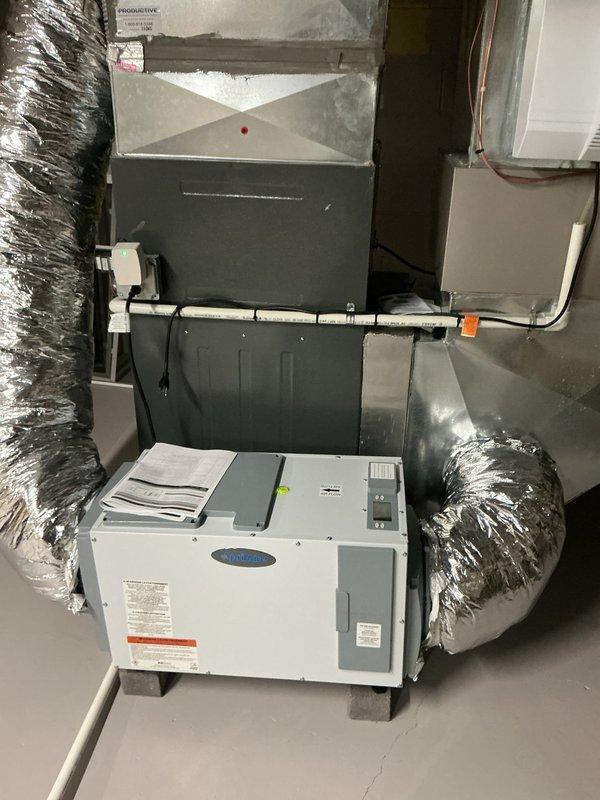 Responded to callback for recurring E2 error code on whole-home dehumidifier unit that was previously serviced. Inspected dehumidifier control board, electrical connections, and drainage system to diagnose the service required error message. Documented system configuration with air handler and dehumidifier installation, verified proper wiring connections and flexible ductwork connections to both units.