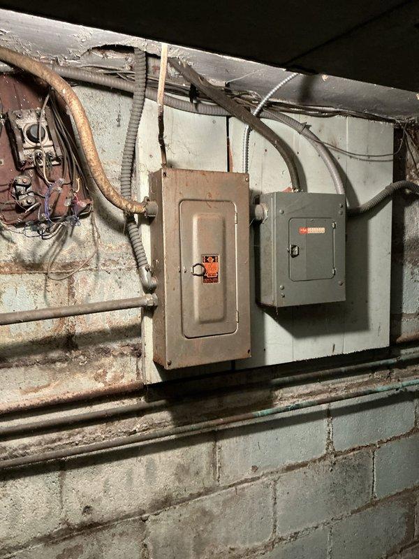 Completed HVAC estimate for air conditioning system replacement in residential property. Assessed existing basement mechanical room infrastructure, including electrical panels, ductwork configuration, and available space for new AC installation. Documented current conditions of utility area showing aged electrical systems, existing furnace with overhead ductwork, and water heater to determine compatibility and requirements for new cooling equipment integration with existing HVAC infrastructure.