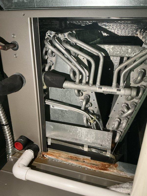 Completed cooling season tune-up on residential HVAC system. Inspection revealed significant rust and corrosion on heat exchanger base and mounting components, indicating prolonged moisture exposure that will require monitoring or future replacement. All accessible components were inspected, refrigerant lines checked, and system operational parameters verified per manufacturer specifications.