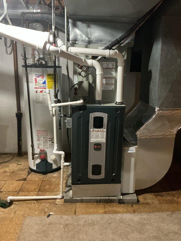 Responded to customer report of air conditioning system not performing well with possible control board issue and abnormal display readings. Upon arrival, inspected basement-mounted HVAC system and observed significant condensation on evaporator coil assembly and surrounding components, indicating active cooling cycle. Evaluated control board operation, verified system diagnostics on display panel, and documented equipment condition including water heater and furnace configuration. Photographed internal components showing moisture accumulation on metallic ductwork, yellow foam insulation, and blower assembly with visible electrical connections and manufacturer identification labels for further assessment and recommended follow-up service.
