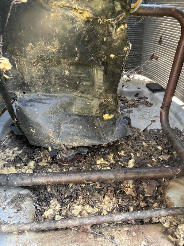 Responded to service call for window AC unit making noise but not cooling properly. Upon inspection, found heavily corroded capacitor with significant dirt and grime buildup, along with severely deteriorated condenser coil housing showing extensive rust, corrosion, and debris accumulation. Replaced failed capacitor, cleaned accessible components, and restored cooling operation to unit.