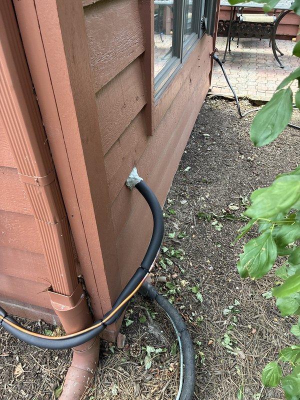 Completed full air conditioning system installation at residential property. Installed new outdoor condenser unit with proper electrical disconnect and fuse protection, utilizing Littelfuse FLNR15A fuses for overcurrent protection. Routed condensate drain line from building using flexible drainage hose connected to existing copper downspout system, ensuring proper water discharge away from foundation. Verified all electrical connections, tested system operation, and confirmed proper airflow through condenser fan assembly.