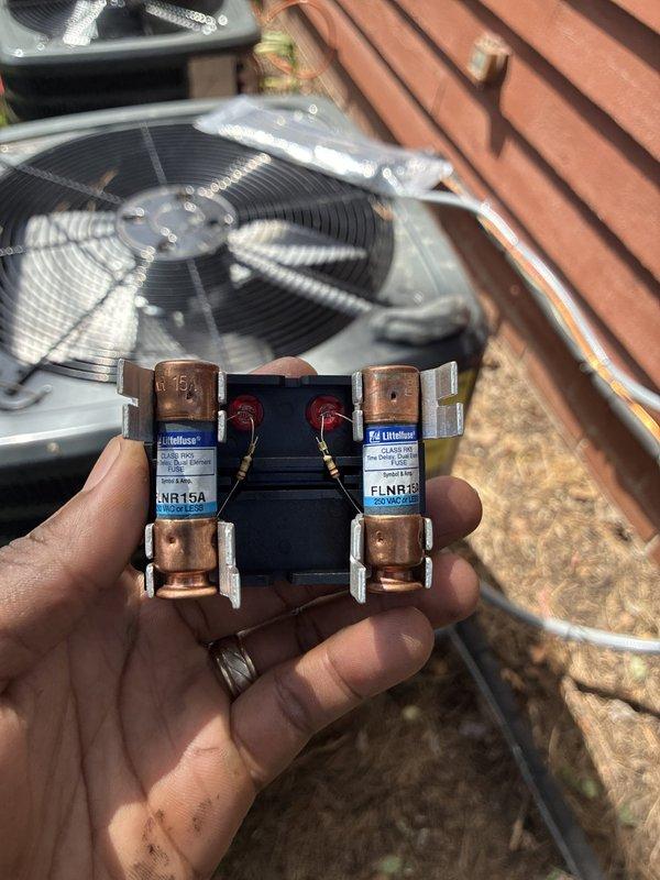 Completed full air conditioning system installation at residential property. Installed new outdoor condenser unit with proper electrical disconnect and fuse protection, utilizing Littelfuse FLNR15A fuses for overcurrent protection. Routed condensate drain line from building using flexible drainage hose connected to existing copper downspout system, ensuring proper water discharge away from foundation. Verified all electrical connections, tested system operation, and confirmed proper airflow through condenser fan assembly.