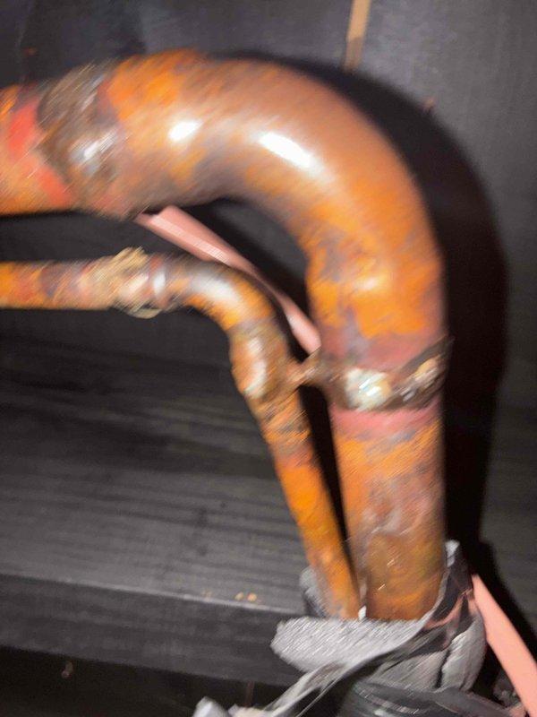 Responded to return service call for frozen window AC unit. Upon arrival, allowed system to fully defrost before conducting inspection. Examined evaporator coil assembly and refrigerant lines, noting copper piping configuration and insulation condition. Identified significant corrosion and rust buildup on pipe joints and connections, particularly at coupling points where moisture accumulation had caused surface deterioration. Documented deteriorated metal components with photographic evidence showing oxidation patterns and compromised pipe integrity. Unit successfully defrosted and inspected for underlying causes of freeze-up condition related to corroded components and potential airflow restrictions.