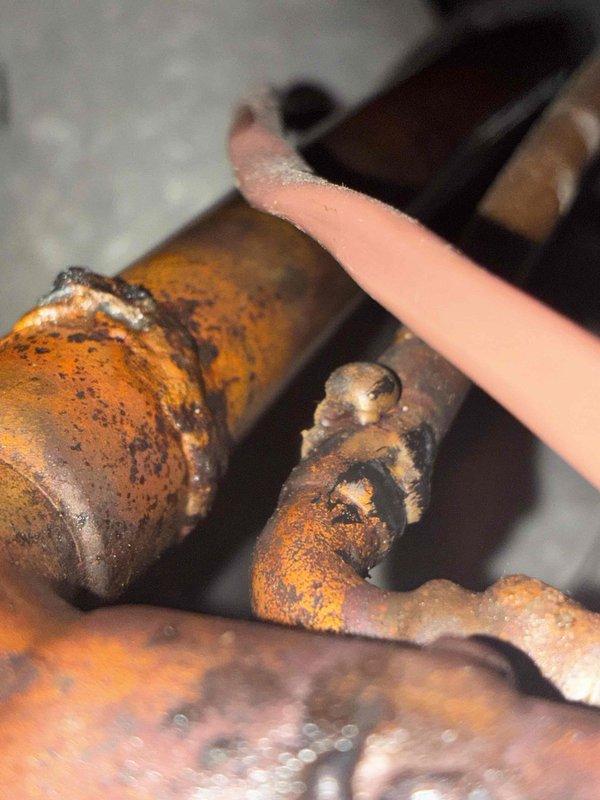 Responded to return service call for frozen window AC unit. Upon arrival, allowed system to fully defrost before conducting inspection. Examined evaporator coil assembly and refrigerant lines, noting copper piping configuration and insulation condition. Identified significant corrosion and rust buildup on pipe joints and connections, particularly at coupling points where moisture accumulation had caused surface deterioration. Documented deteriorated metal components with photographic evidence showing oxidation patterns and compromised pipe integrity. Unit successfully defrosted and inspected for underlying causes of freeze-up condition related to corroded components and potential airflow restrictions.