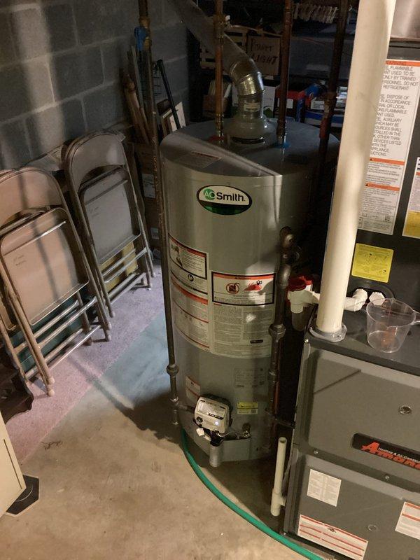 Responded to call regarding excessively hot water from A.O. Smith tanked water heater causing scalding conditions at fixtures. Upon arrival, performed visual inspection of unit and surrounding plumbing connections in basement utility area. Assessed water heater operation, temperature settings, and pressure relief valve function. Customer reported issue developed progressively over previous week with no adjustments made to equipment. Documented equipment condition and configuration with photographs showing copper supply lines, pressure relief valve, and overall installation setup for service records.