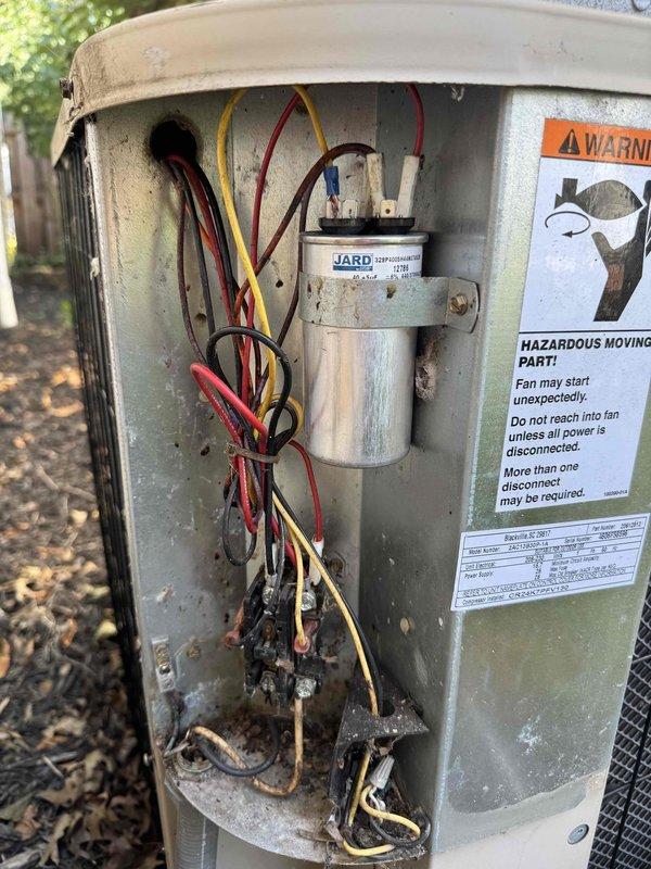 Responded to service call for air conditioning system not operating. Upon arrival, performed visual inspection of outdoor condenser unit. Removed access panel to examine electrical components and wiring. Discovered severe fire damage in electrical compartment with extensive charring and melted wire insulation at bottom of unit. Multiple wire connections showed burn damage with blackened material accumulation. JARD capacitor present with connected wiring affected by thermal damage. Unit deemed unsafe to operate due to fire hazard and electrical component failure. Documented damage with photographs for customer review and insurance purposes. Advised customer that system requires immediate replacement of damaged electrical components and thorough safety inspection before restoration of service.