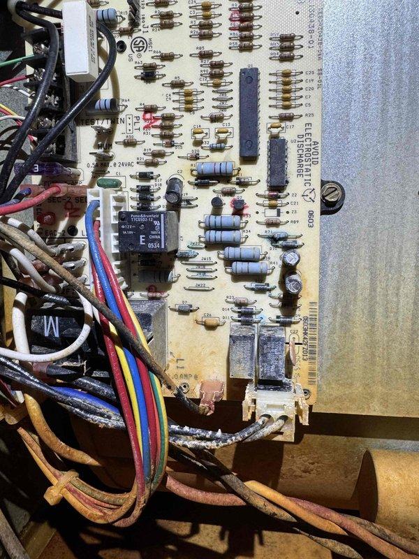Responded to no-cooling complaint with condenser fan cycling off and water discharge from basement area. Upon arrival, inspected outdoor condensing unit and found system had been shut down by customer. Examined control board showing signs of age and potential relay failure affecting condenser fan operation. Water leakage indicated condensate drain issue or secondary drain pan overflow from system shutdown. Inspected PCB components including relays, resistors, and wiring connections for signs of failure or deterioration. Evaluated outdoor unit installation on concrete pad with proper clearances maintained. Addressed electrical control malfunction preventing proper condenser fan operation, which was causing inadequate heat rejection and loss of cooling capacity.