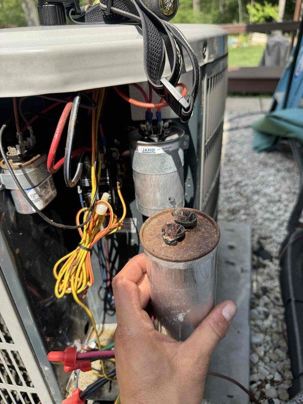 Responded to no cooling condition on 11-year-old residential air conditioning system affecting entire home. Upon inspection of outdoor condenser unit, identified failed dual run capacitor exhibiting severe corrosion and rust on terminals and casing. Removed defective capacitor and installed new JARD replacement capacitor with proper microfarad rating. Verified all electrical connections, tested system operation, and confirmed proper cooling restoration to residence.
