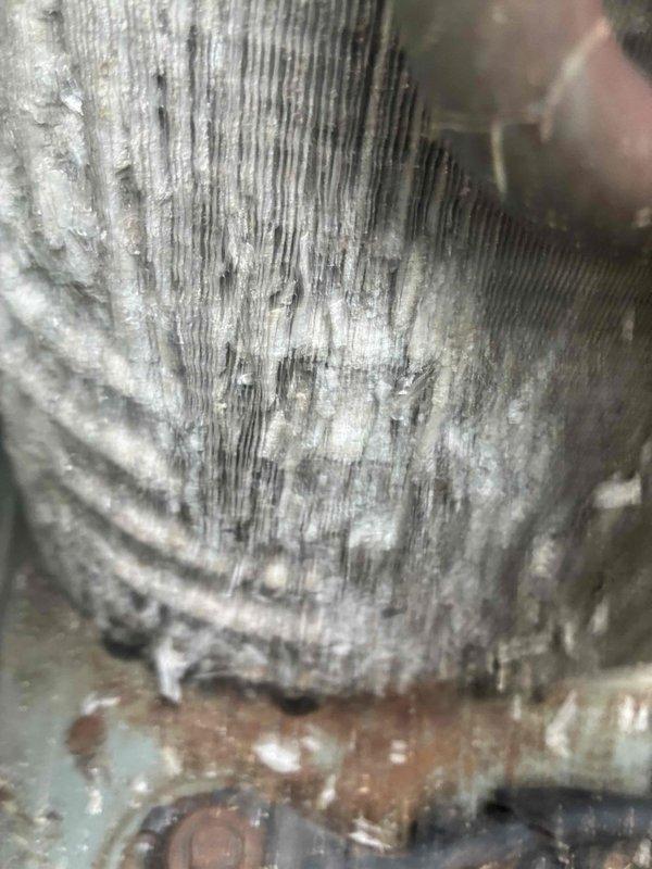 Performed HVAC maintenance service on air conditioning system. Upon inspection, found evaporator coils heavily contaminated with dust and debris buildup, significantly restricting airflow and reducing system efficiency. Coil fins showed extensive accumulation of particulate matter with matted, fuzzy appearance throughout. Identified corroded metal housing and base plate with visible rust spots. Refrigerant lines displayed oxidation and patina consistent with prolonged exposure to moisture. Observed mineral deposits and white/gray oxidation on heat exchanger fins with vertical streaking patterns indicating condensation issues. Air filter showed signs of requiring replacement. Cleaned evaporator coils thoroughly to restore proper airflow and heat transfer capability. Addressed corrosion concerns on copper refrigerant piping and system components. System restored to operational condition with improved efficiency.