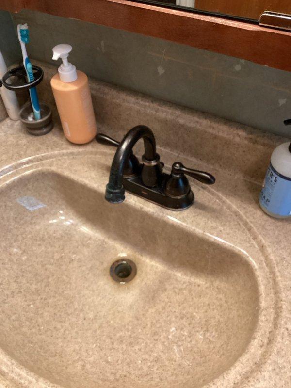 Conducted site assessment for upcoming plumbing fixture replacement project. Evaluated existing bathroom installations including main shut-off valve, two faucet assemblies, bathroom sink with integrated countertop, and shower head fixture requiring replacement. Documented current conditions of oil-rubbed bronze tub/shower controls, black two-handle lavatory faucet, and beige cultured marble vanity top with integrated basin. Reviewed scope of work for fixture changeouts and custom channel installation, noting all replacement parts provided by property owner.