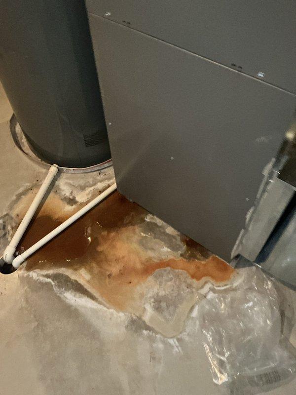 Responded to service call for 13-year-old air conditioning system not cooling effectively and water accumulation near furnace area. Upon inspection, found severely restricted airflow due to clogged air filter requiring immediate replacement with new 20x24x1 filter. Identified condensate drainage issue causing water pooling on floor around HVAC cabinet, evidenced by significant water staining and discoloration on flooring surface. Cleared condensate drain line blockage and verified proper drainage through PVC drain piping. System tested and confirmed restored cooling capacity and proper condensate removal.