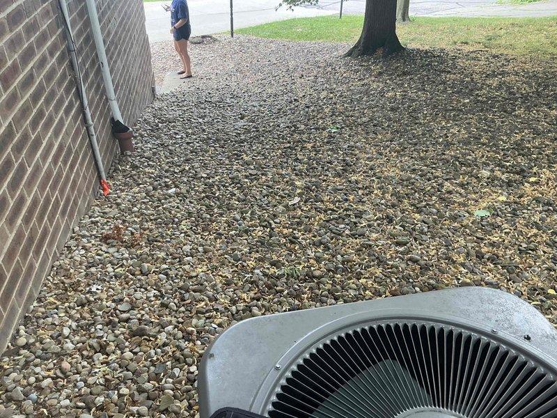 Provided replacement estimate options for existing residential air conditioning system at rental property. Evaluated current outdoor condensing unit positioned on gravel pad adjacent to building foundation and assessed electrical disconnect and conduit configuration mounted on exterior brick wall. Documented equipment condition and installation setup with photographs for property owner review and decision-making on replacement versus repair options.