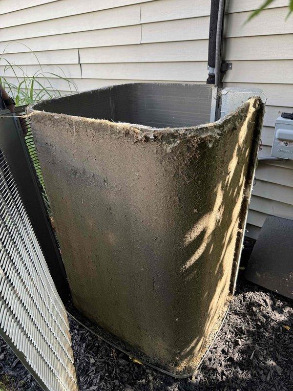 # HVAC Cooling Maintenance Completed

Performed routine preventive maintenance on residential air conditioning system as part of ongoing service agreement. Removed and inspected condensing unit cover, which displayed significant weathering, algae growth, and deterioration along top edge with jagged breaks in material. Accessed internal components by removing exterior shroud to inspect condenser coils, fins, and electrical connections. Documented equipment condition showing aged exterior panels with substantial environmental exposure, oxidation, and biological growth accumulation. Unit operational at time of service with all internal components accessible for standard maintenance procedures.