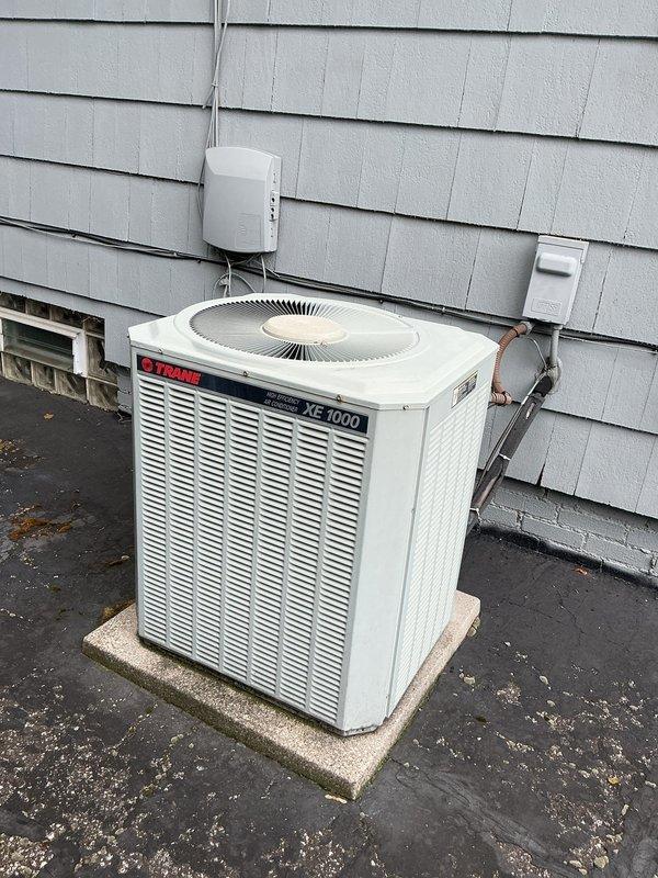 # HVAC Maintenance Service Completed

Performed comprehensive preventive maintenance on a Trane XE 1000 outdoor condensing unit as part of a recurring cooling system service plan. Conducted thorough inspection of all electrical components within the unit's compartment, verifying integrity of wire connections, terminal blocks, capacitors, and relay assemblies. All electrical connections were found secure with proper wire nut installations. Examined refrigerant line connections and mounting hardware along the building exterior, confirming secure attachment and no visible signs of refrigerant leakage. Inspected condenser coil through ventilation louvers and verified fan motor operation. Unit exterior and mounting pad were in satisfactory condition with adequate clearance maintained. System operating within normal parameters with no immediate repairs required at time of service.