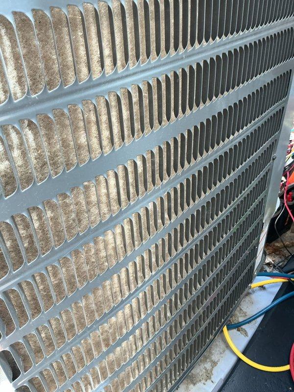 Responded to service call for non-operational Goodman AC unit with reported loud startup noise. Performed comprehensive maintenance inspection on 9-year-old system. Found significant debris accumulation and dirt buildup on condenser coil fins, with heavy contamination on one side restricting airflow and reducing heat exchange efficiency. Cleaned condenser coils thoroughly to restore proper airflow and system performance. Inspected electrical connections and refrigerant lines. Addressed loud startup noise concern through system evaluation. Unit restored to operational condition with improved cooling efficiency following coil cleaning and maintenance procedures.