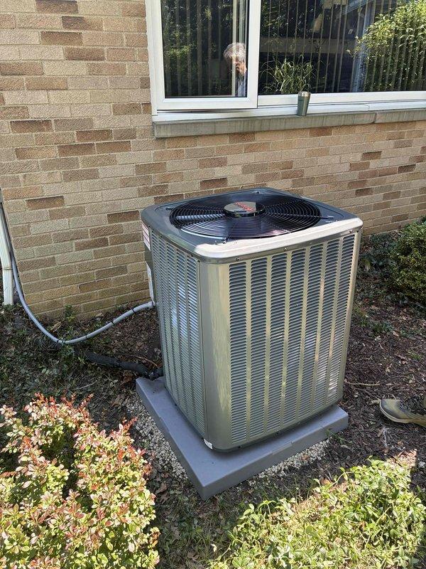 Completed full HVAC air conditioning system installation including outdoor condenser unit mounted on concrete pad with proper refrigerant line routing through exterior wall. Connected new A/C system to existing furnace infrastructure with appropriate ductwork integration and electrical connections. System tested and verified operational with proper airflow and cooling capacity.